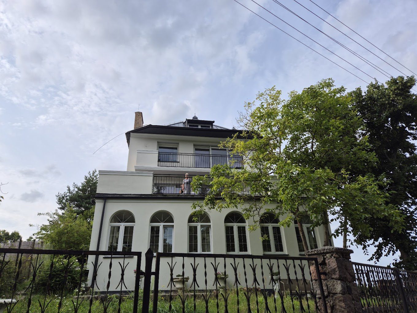 biały dom wśród zieleni na tle lekko zachmurzonego nieba