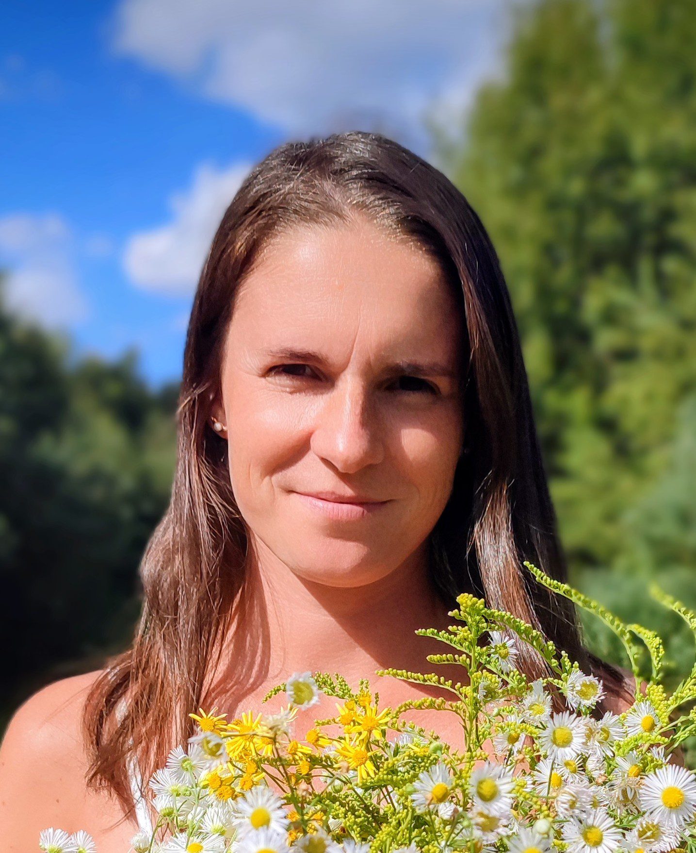 brunetka wśród natury trzyma bukiet polnych kwiatów